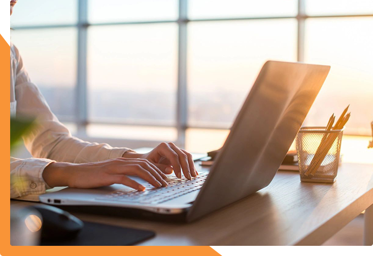 Person typing on laptop by window.